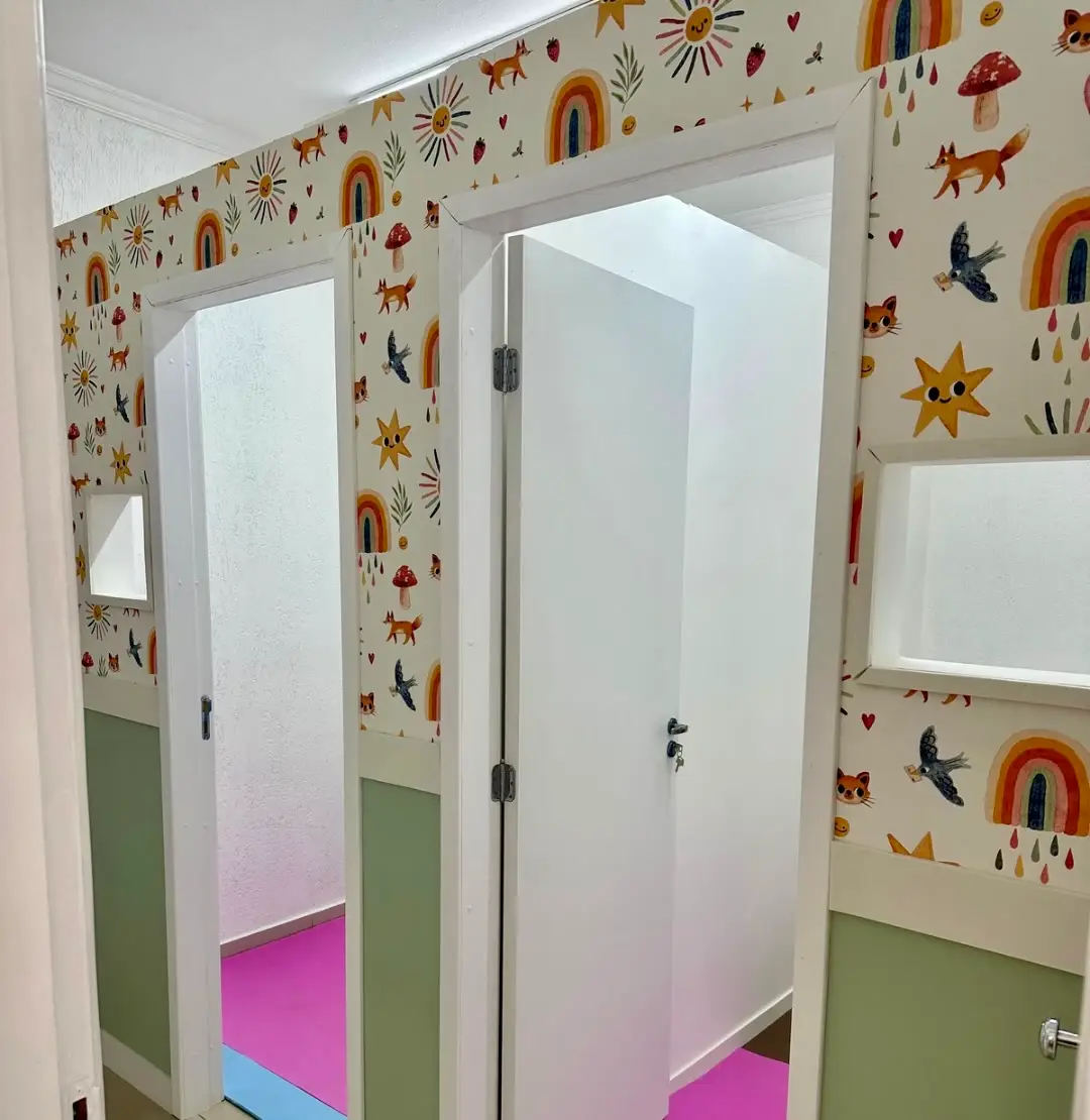 Corredor com papel de parede ilustrado com arco-íris e portas das salas